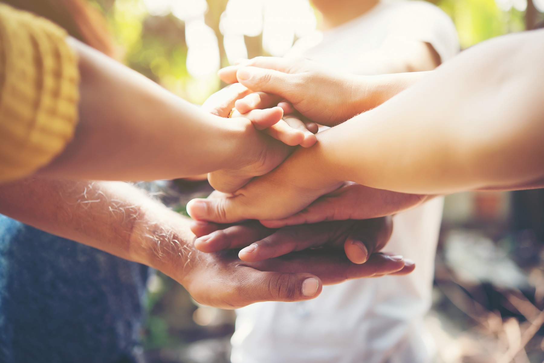 Close up of young people putting their hands together. Team with stack of hands showing unity and teamwork.